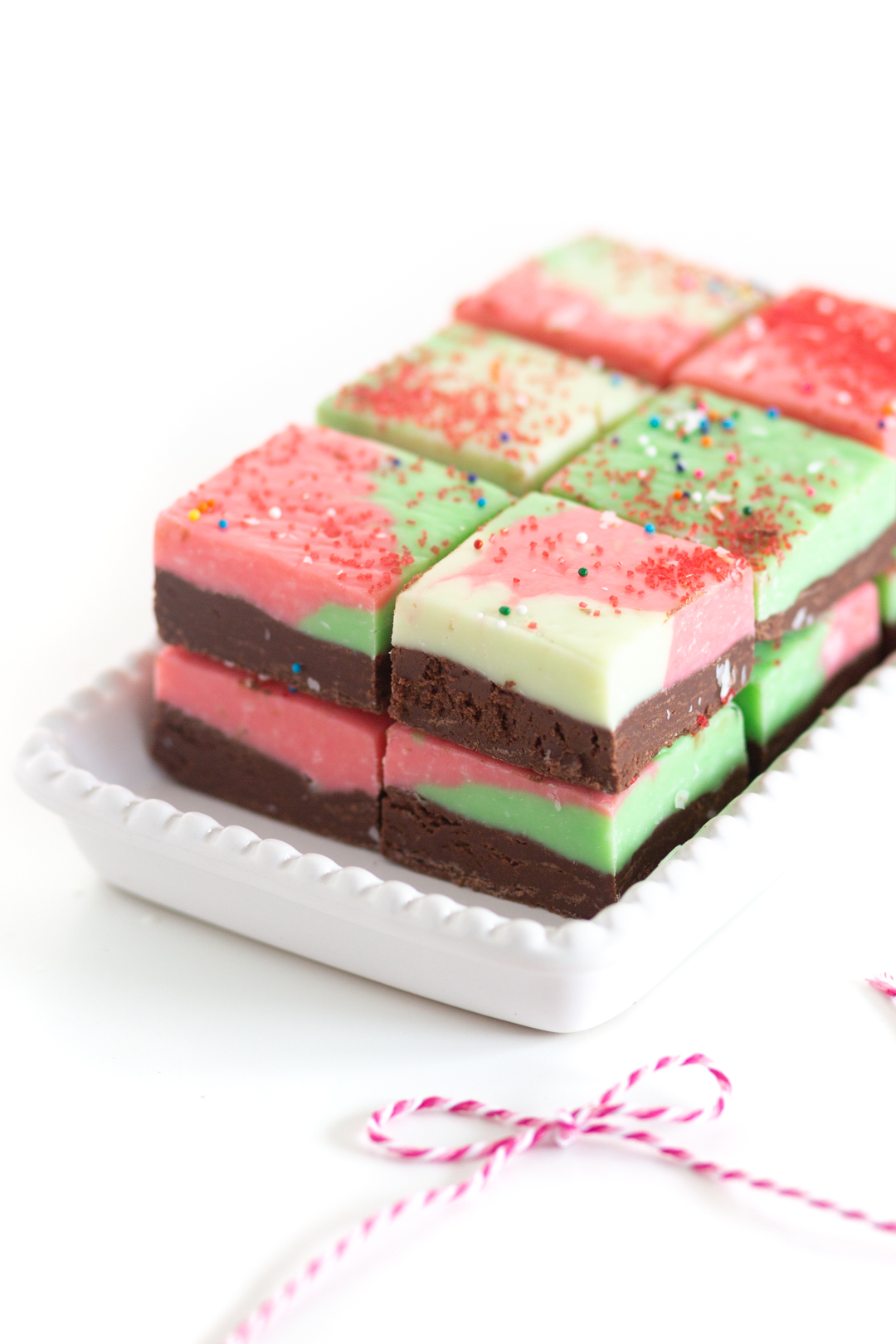 downward angle of fudge being served on a very small platter. red, green and chocolate swirled fudge with red sprinkles on top.