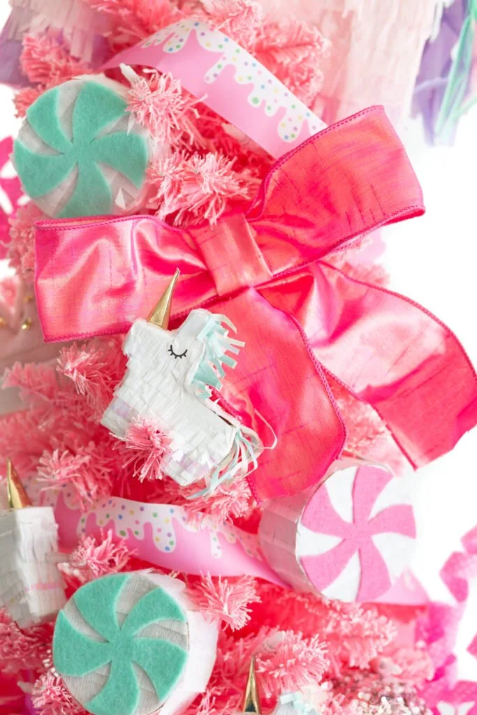 really cute tiny unicorn pinata on a candy colored pink christmas tree with fluffy pink ribbon decor and mini peppermint pinatas