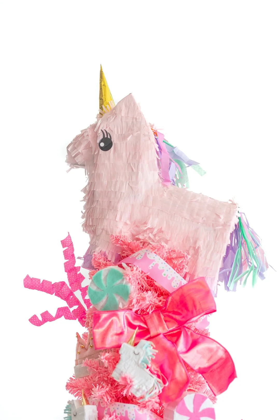 up close view of a medium sized unicorn pinata being used as a christmas tree topper on a small think pink christmas tree