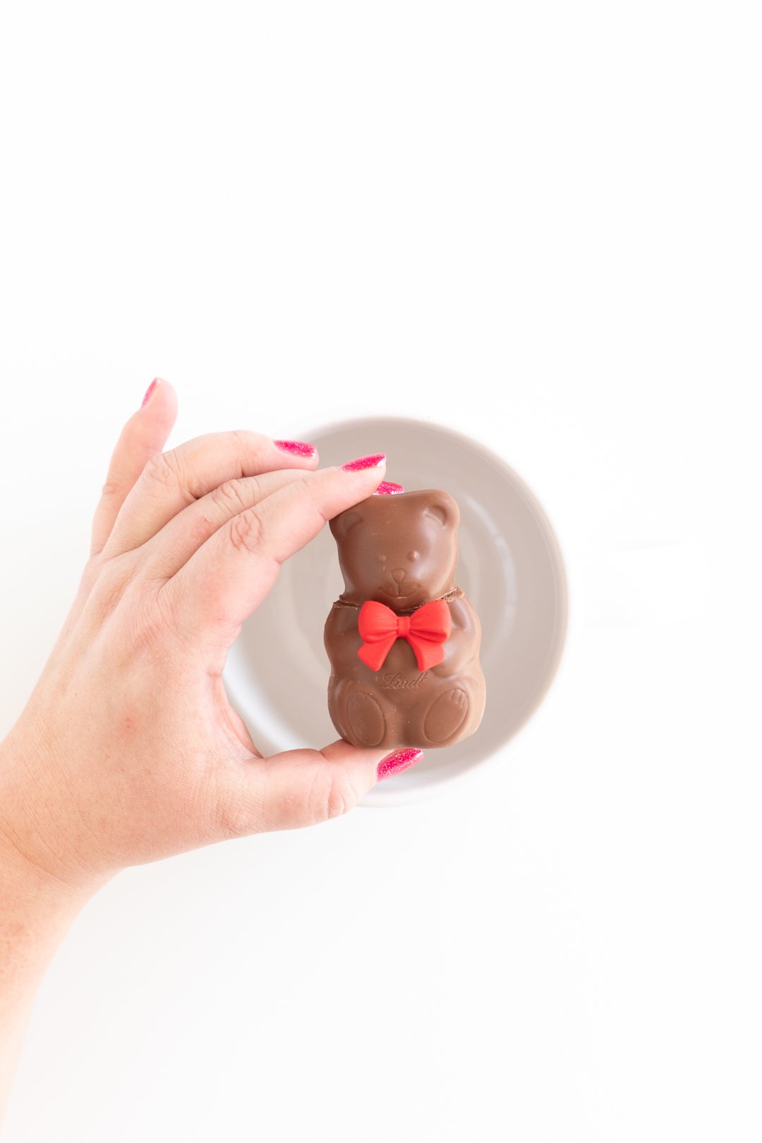 woman holding a chocolate teddy bear hot cocoa melt over an empty white mug