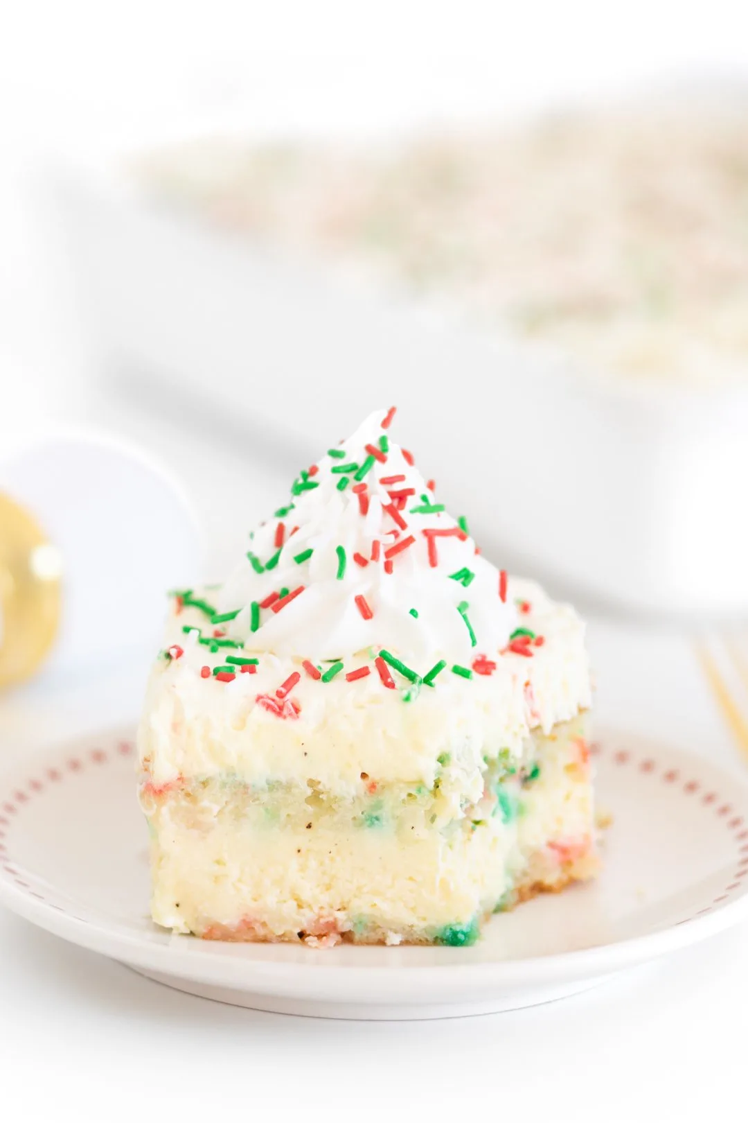 pretty slice of layered vanilla cake with red and green christmas sprinkles