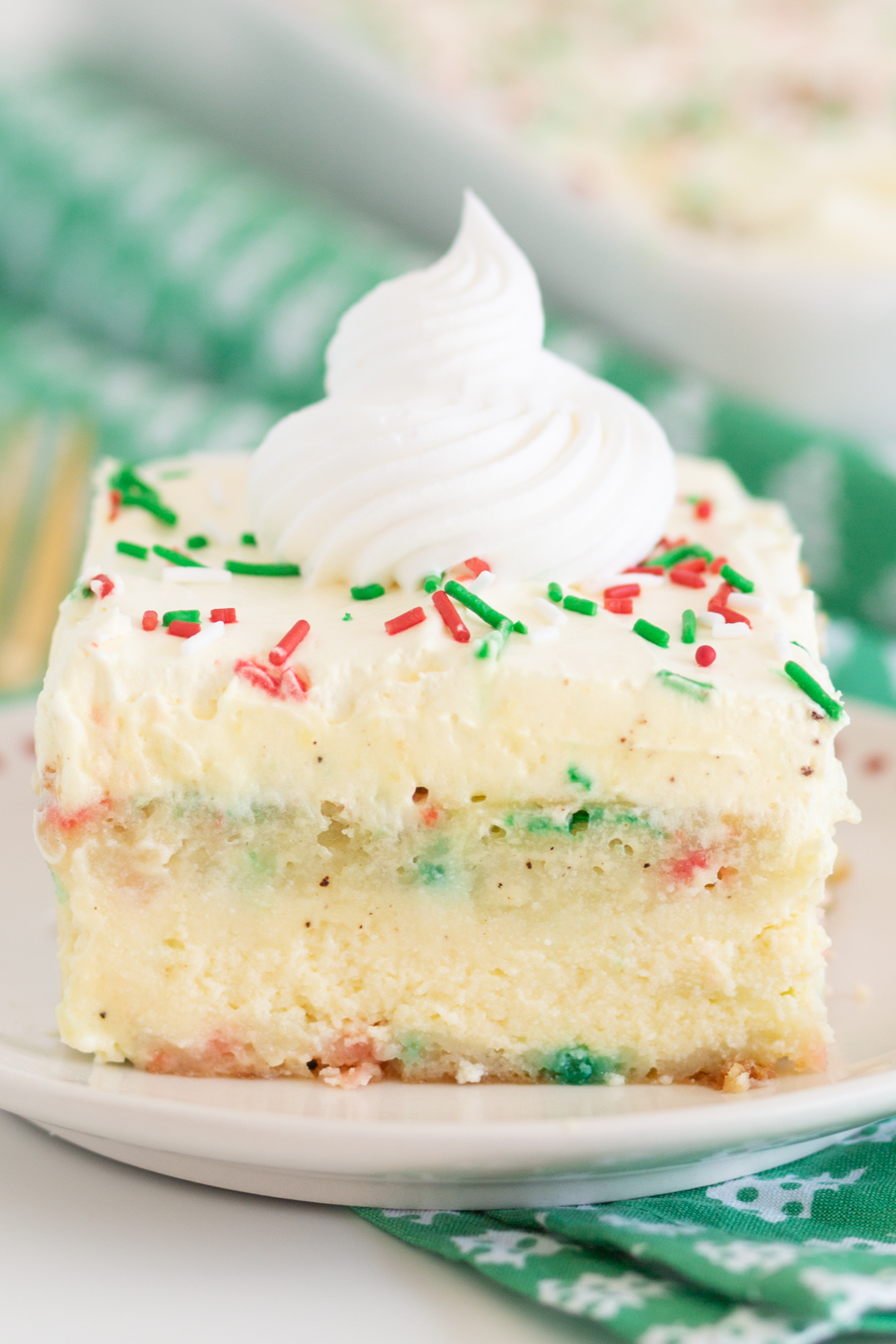up close photo of a chrismtas themed vanilla cake with layers topped with red and green sprinkles.