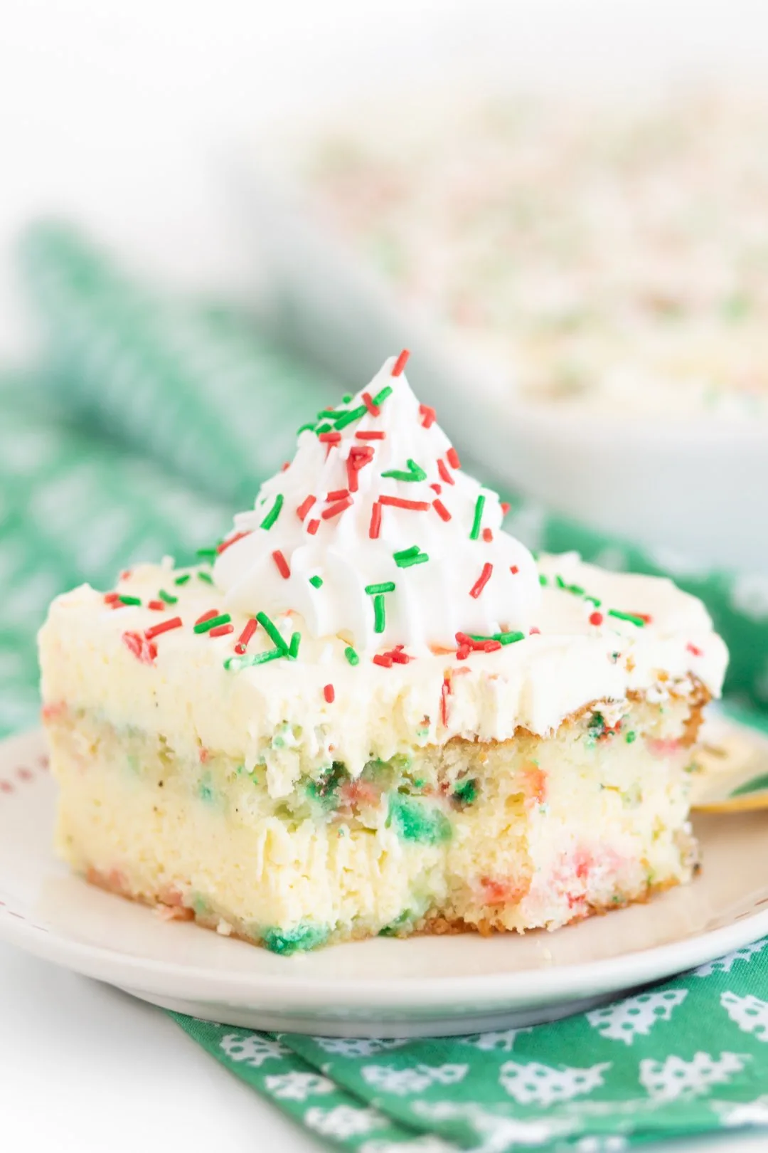 close up of christmas layered love cake with red and green sprinkles and a dollop of whipped cream
