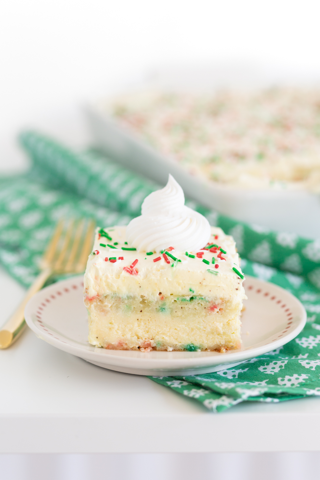slice of layered cake on a small festive dish setting on top of a green christmas tree cloth napkin and a gold fork