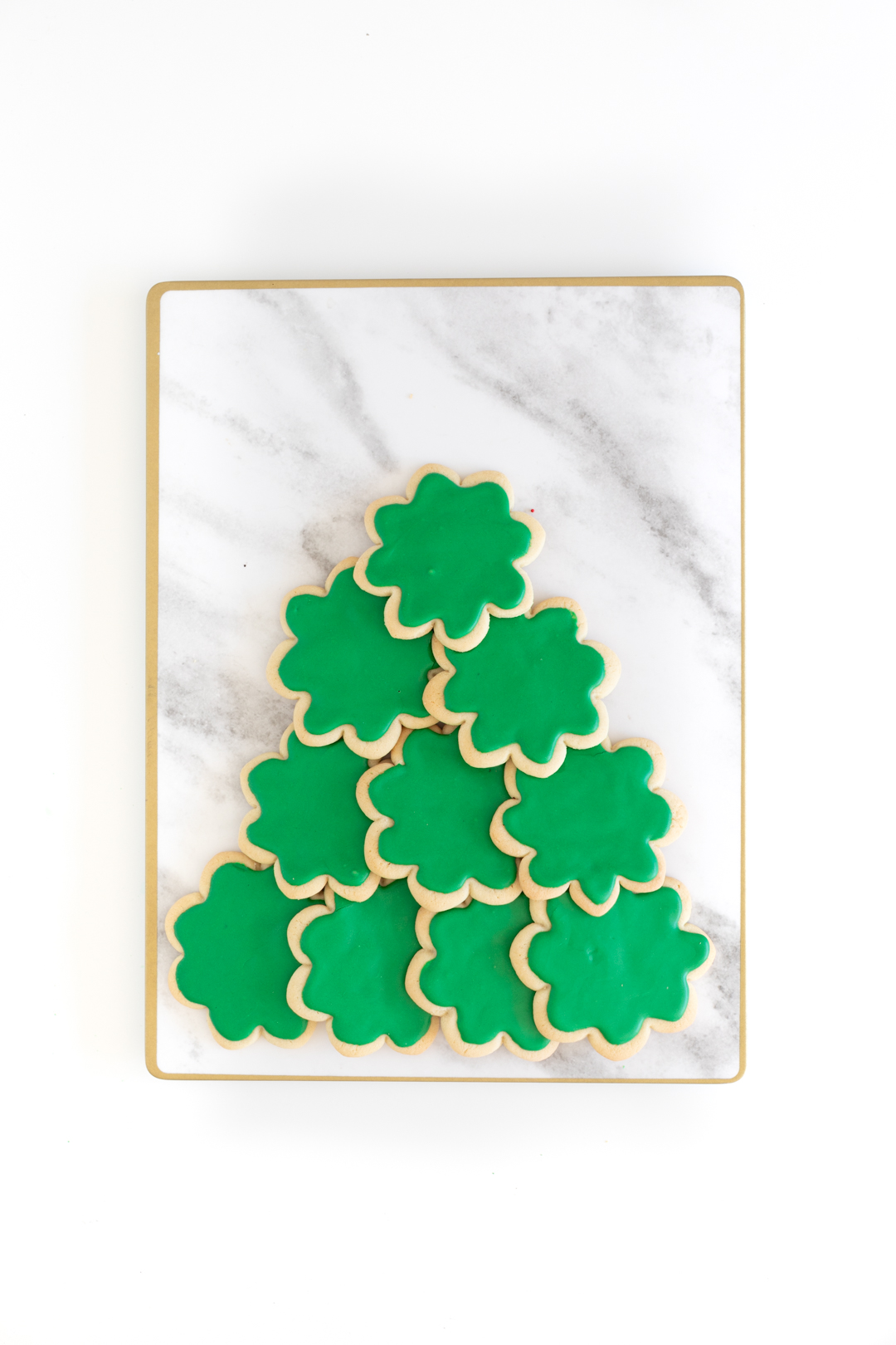 building a christmas tree platter using green frosted sugar cookies that were made with a flower shaped cookie cutter