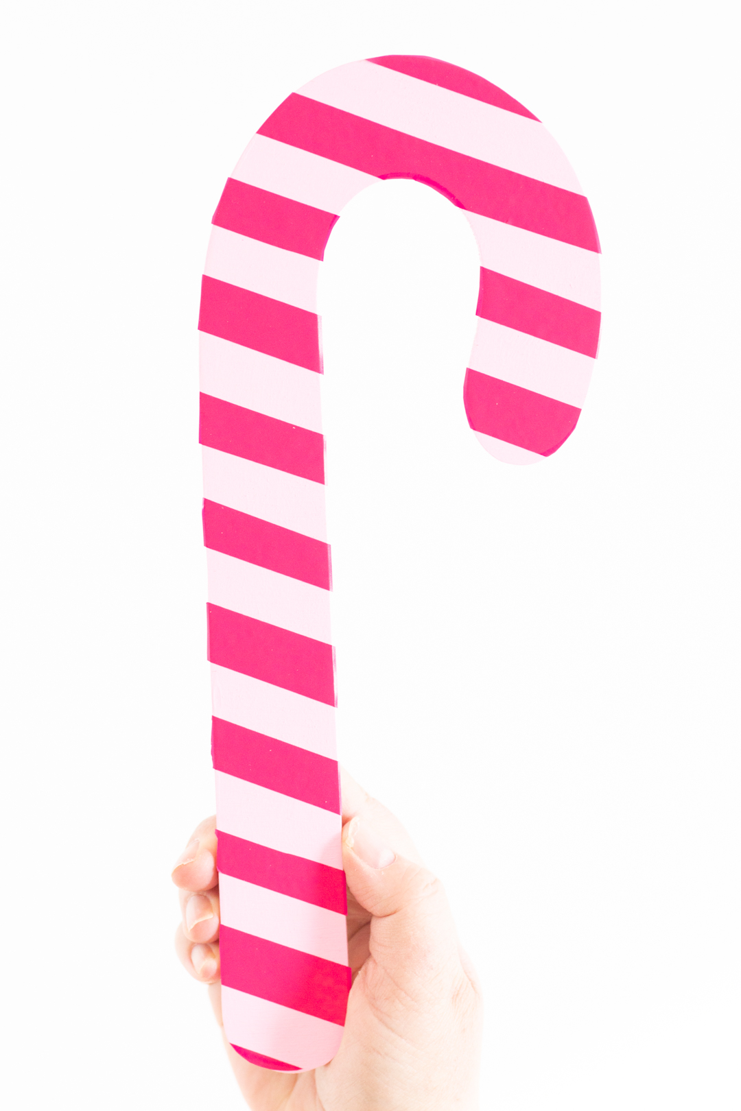 woman holding a diy pink candy cane using cricut fuchsia vinyl stripes