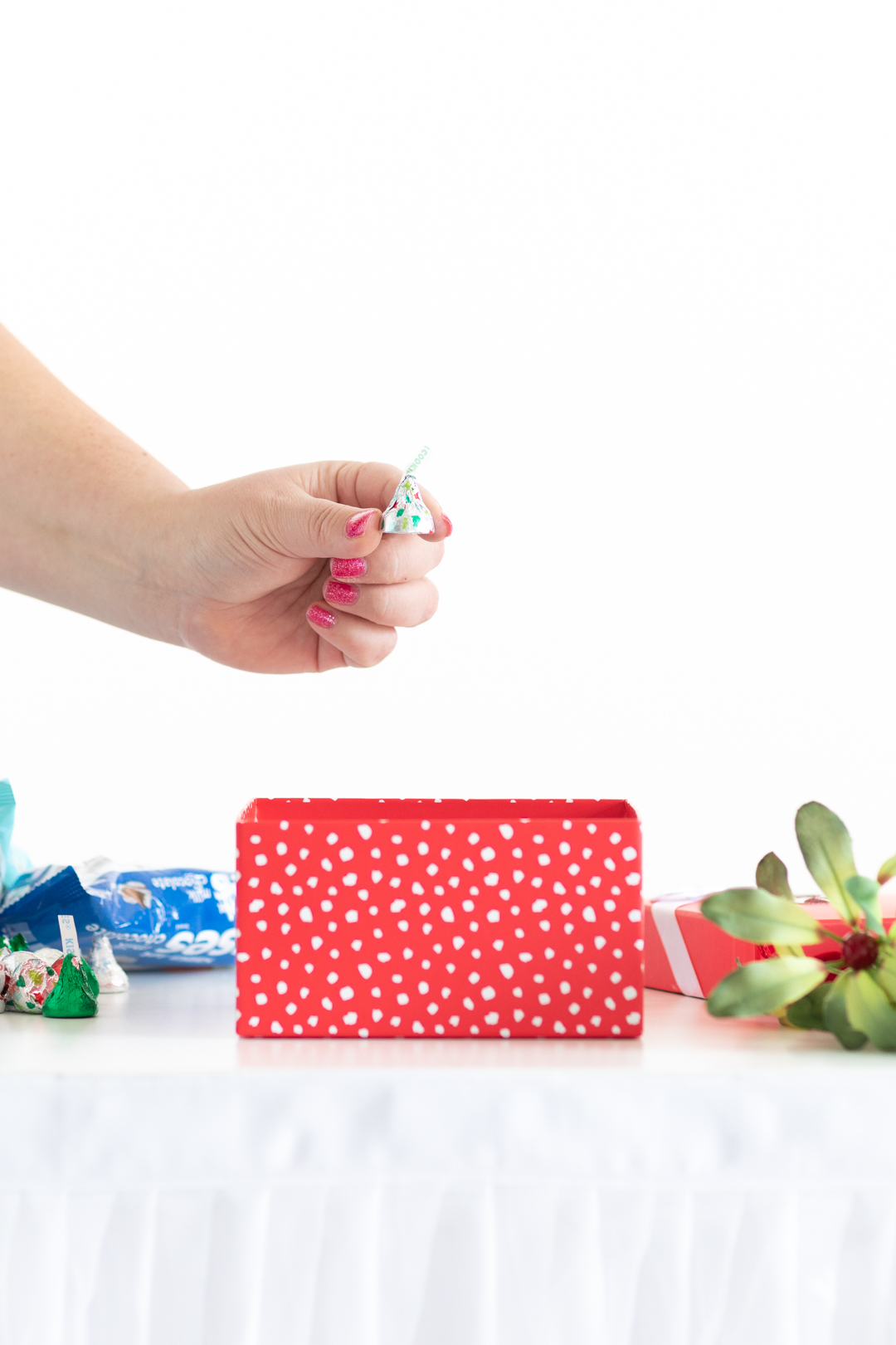 woman holding a single hershey kiss to be placed into a red gift box