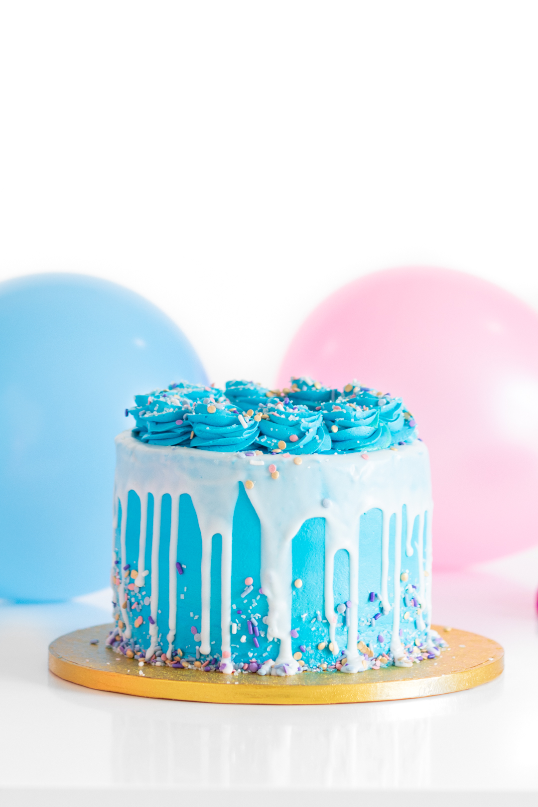 pretty blue colored cake with white icing drip set on a gold cake platter