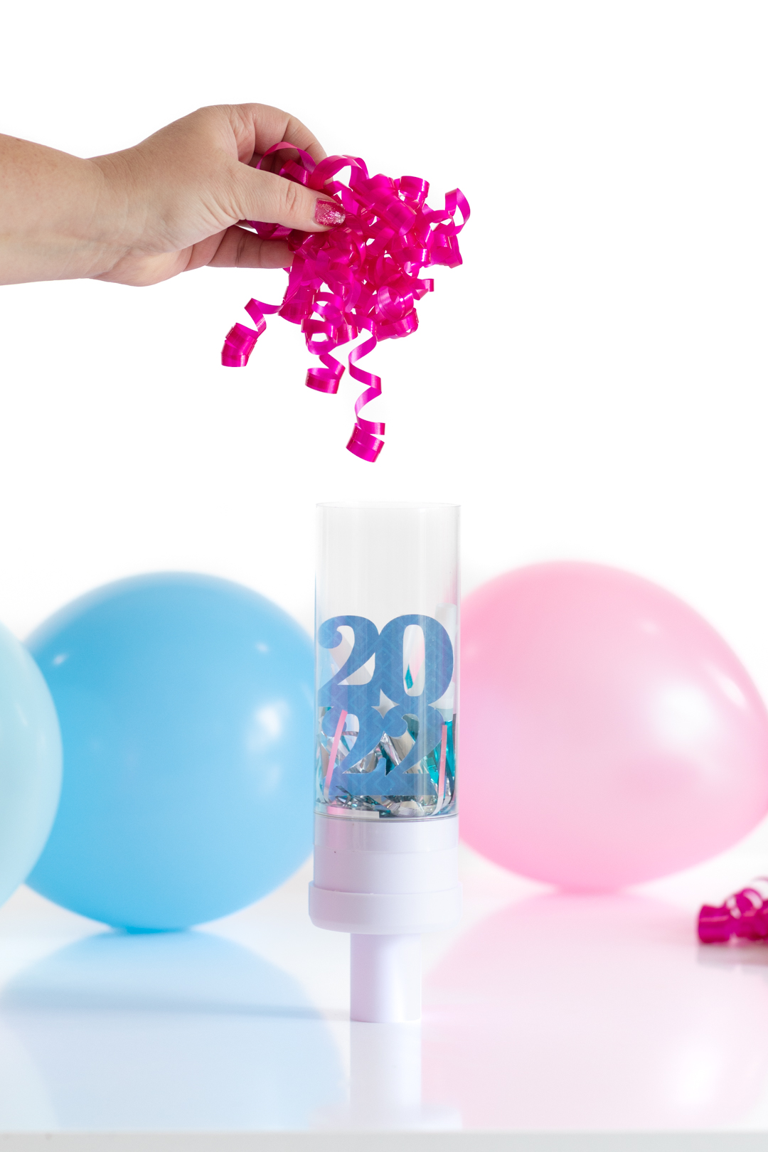 adding bright pink curly gift bow into a clear tube as a gift. 2022 decoration inside the tube, too.