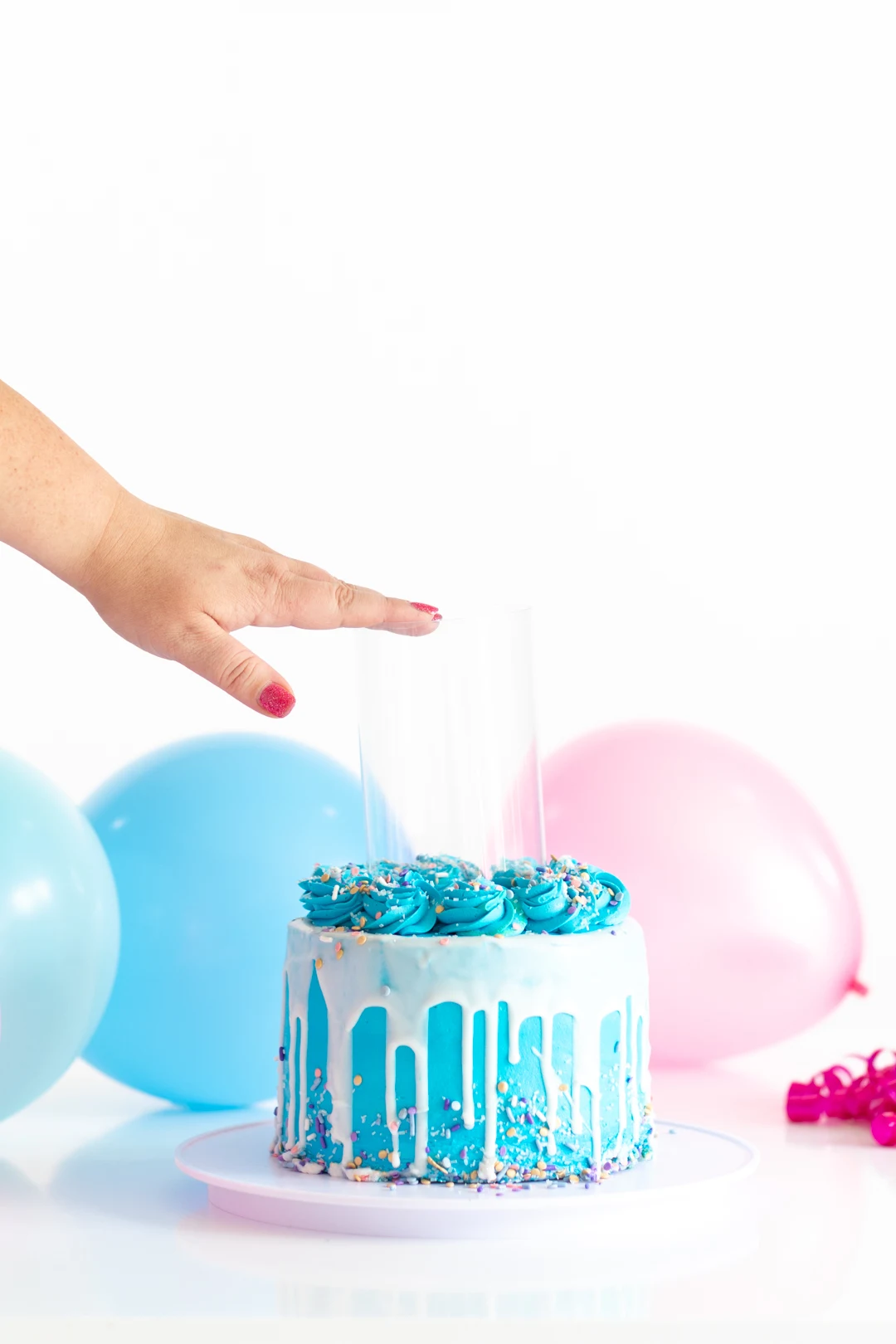 pressing a clear tube into the center of a small blue cake to remove the center to enable it to be used in a surprise cake stand
