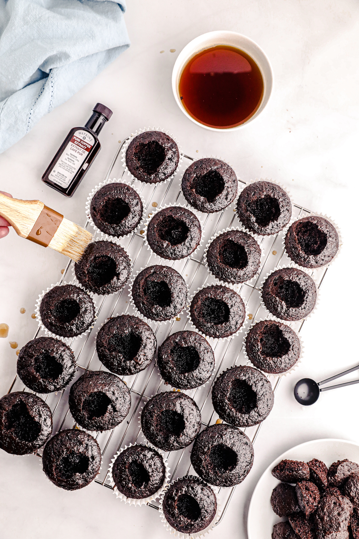 using a foodbrush to add simple syrup to a batch of chocolate cupcakes