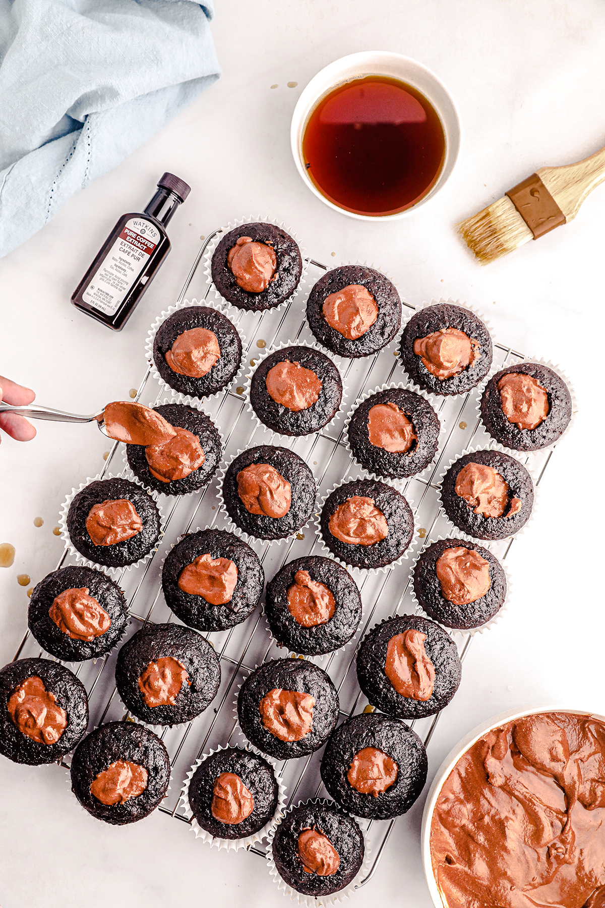 woman spooning chocolate mousse into the centers of chocolate cupcakes