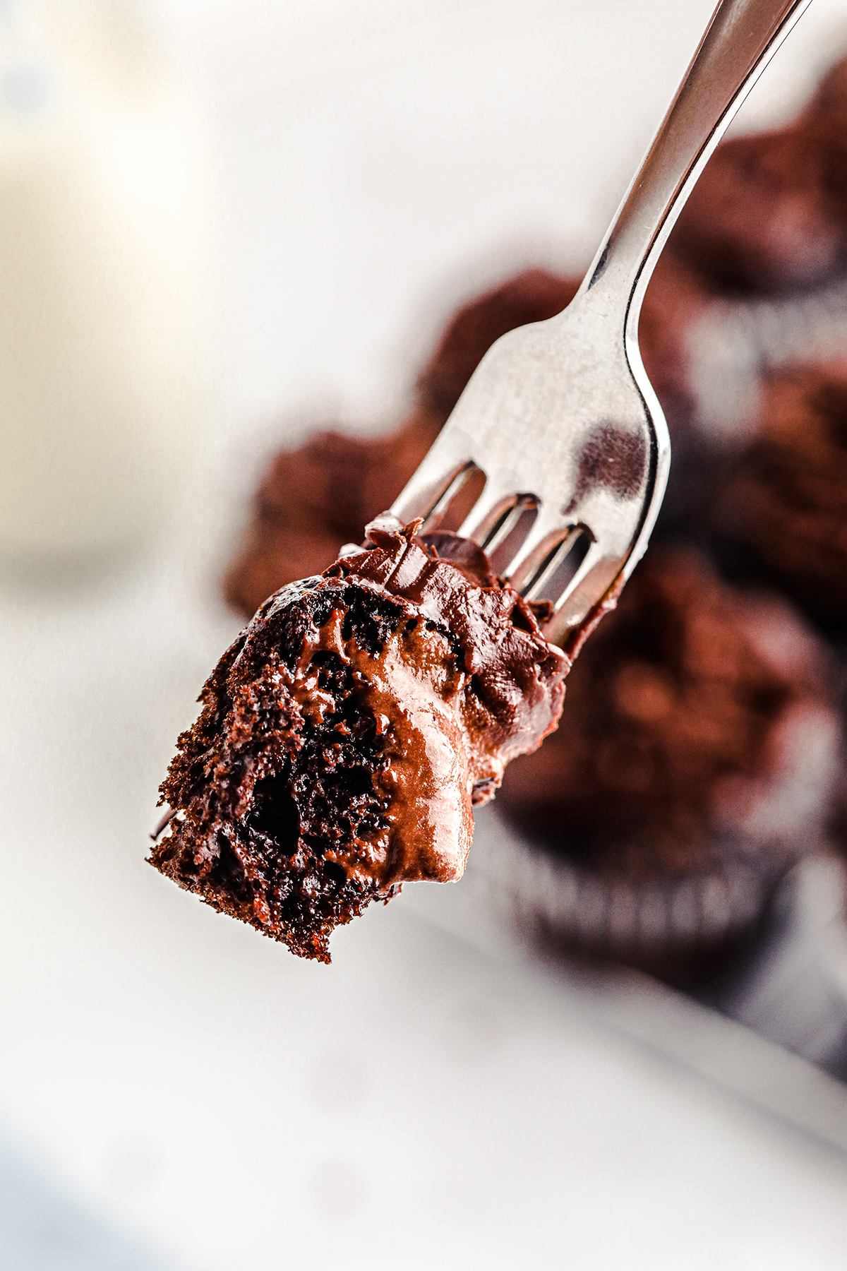 close up view of fork full of chocolate cupcake with chocolate frosting