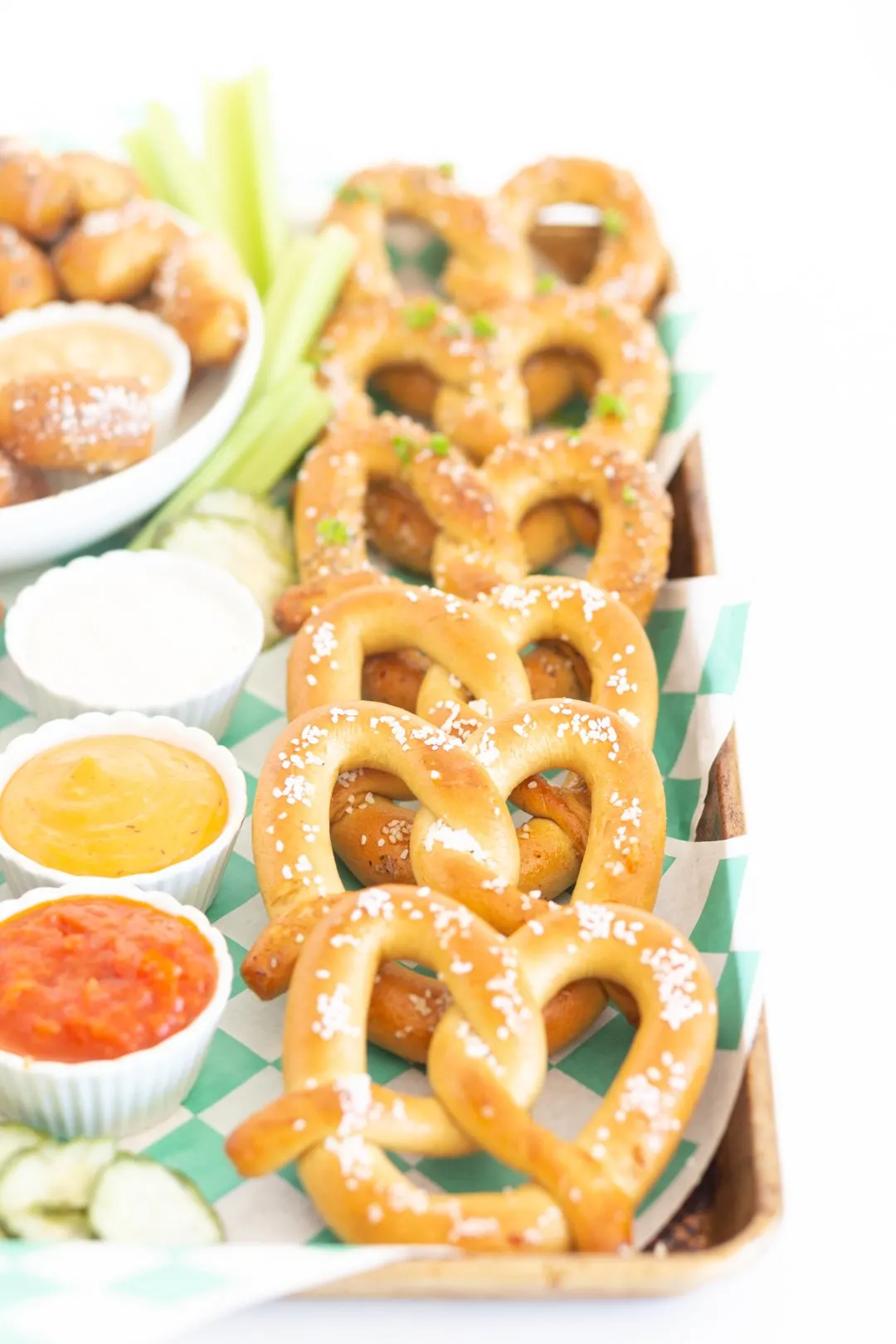 view of soft pretzel snack board with salted pretzels and herbed pretzels lined up next to a variety of dipping sauces