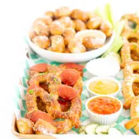 angled down view of game day snacking board loaded with soft pretzel options in different shapes and flavors. Dipping sauces in small dipping dishes.