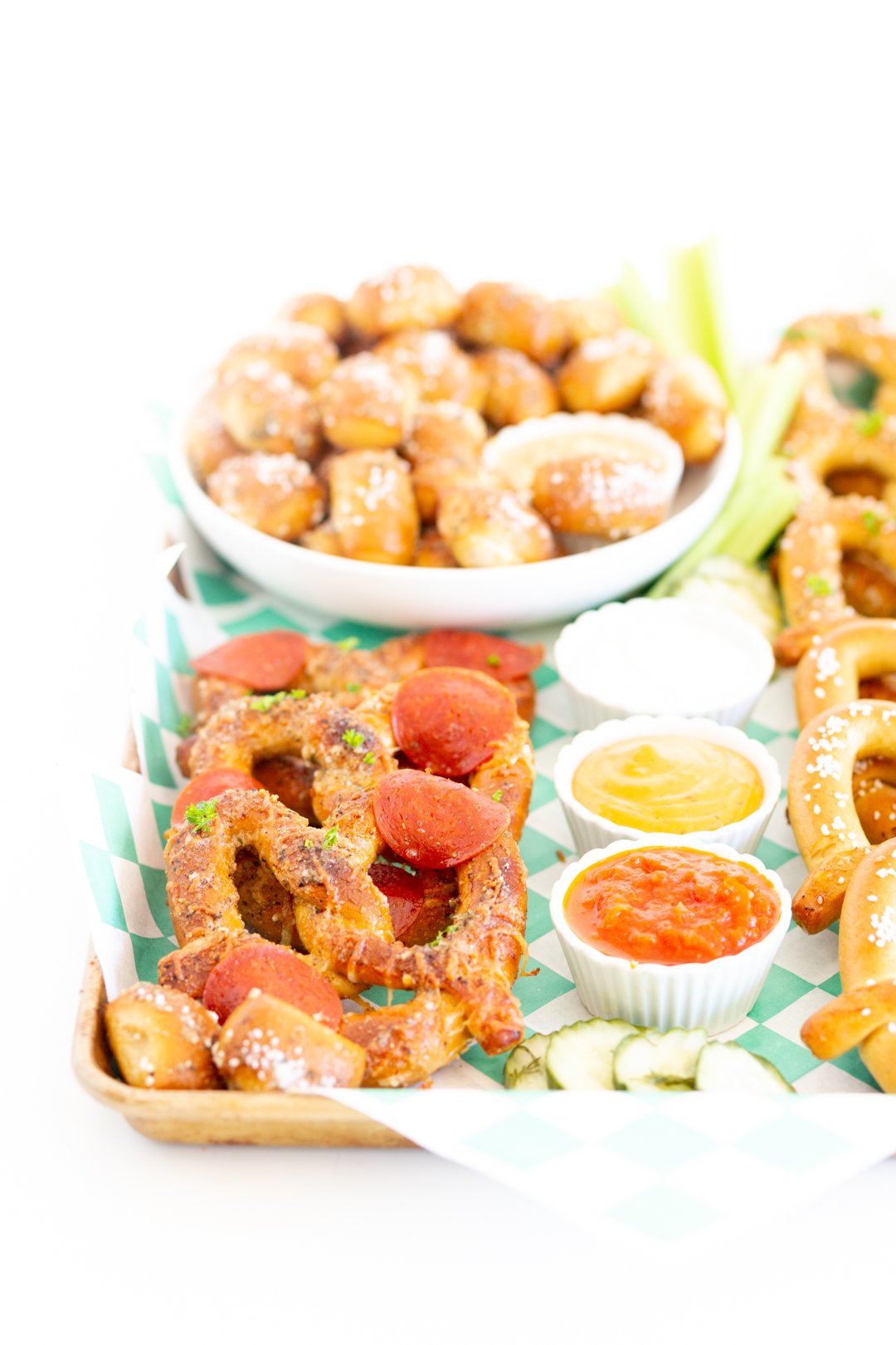 angled down view of game day snacking board loaded with soft pretzel options in different shapes and flavors. Dipping sauces in small dipping dishes.