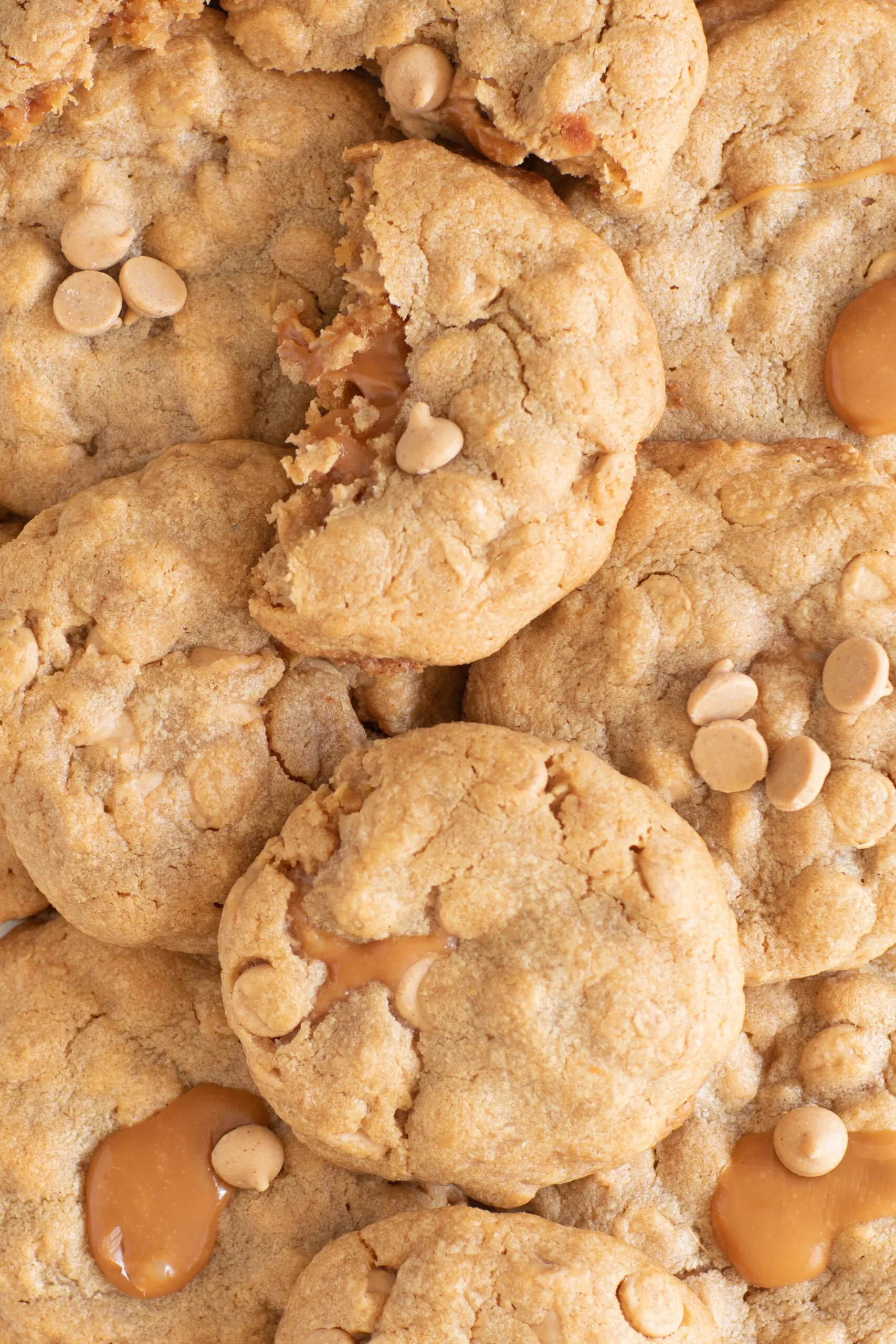 photo of a bunch of soft peanut butter cookies stuffed with caramel with caramel oozing out and peanut butter chips