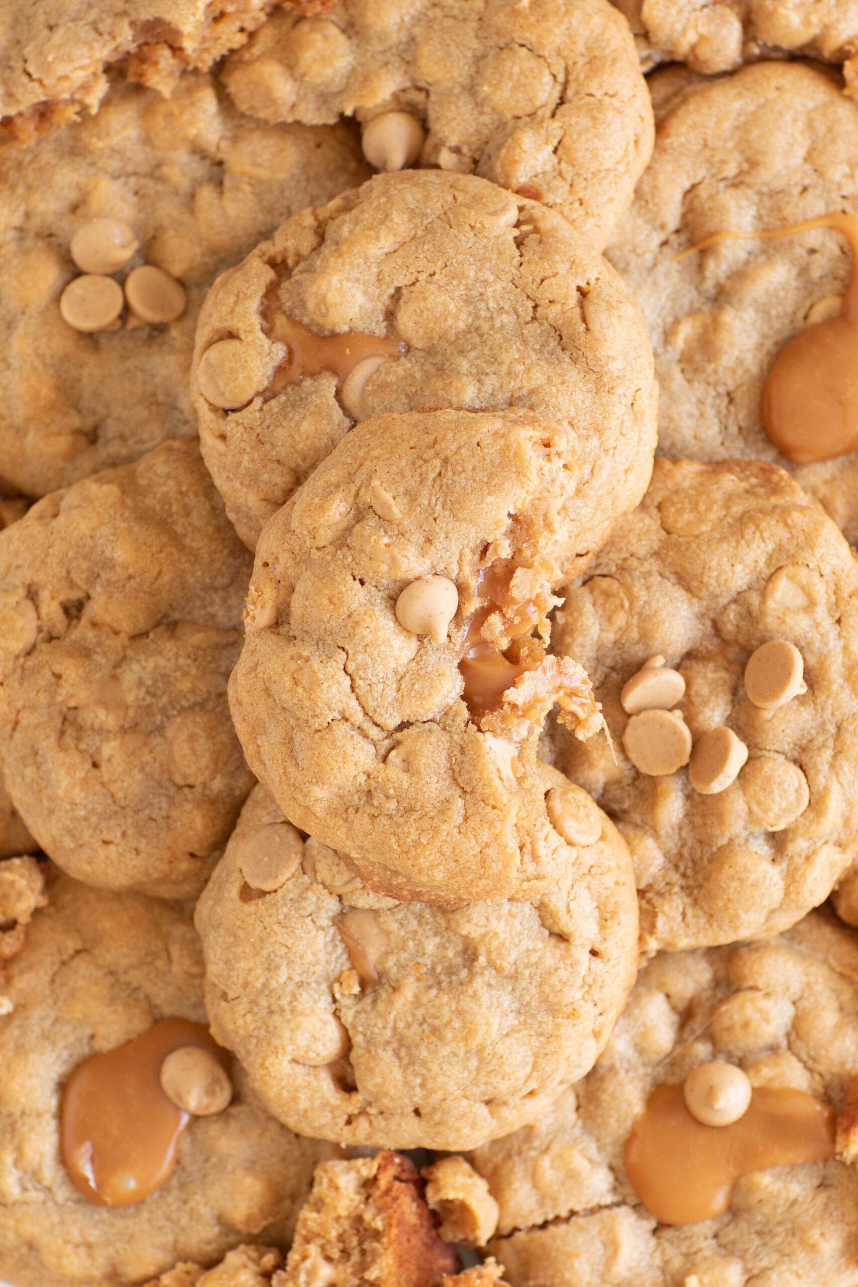 stack of peanut butter cookies stuffed with caramel. halved cookie revealing gooey caramel in the center