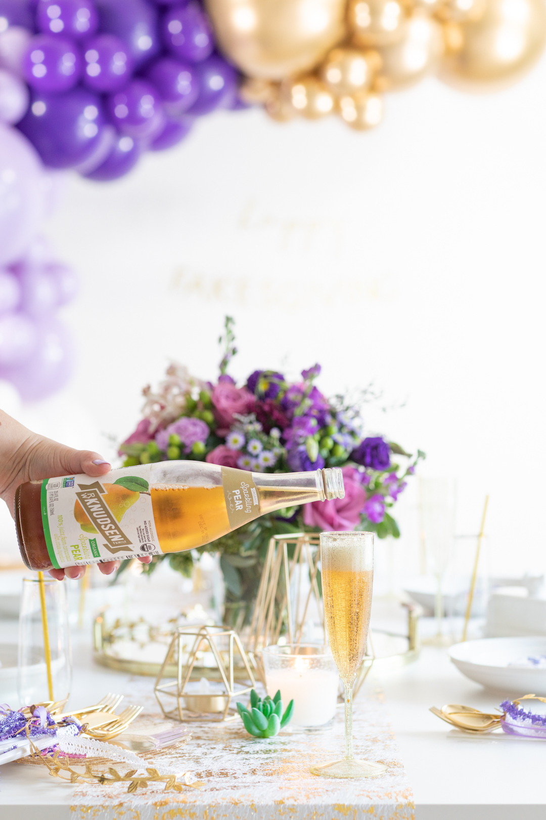 woman pouring sparkling pear juice into a gold tinted tall cocktail cup