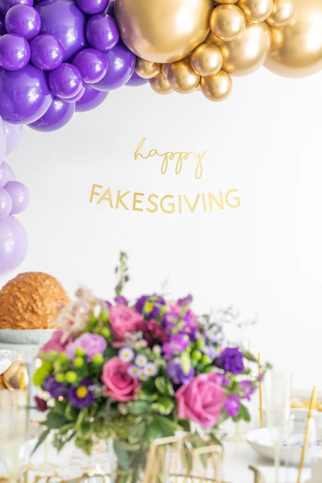 happy fakesgiving gold banner in focus as part of a fakesgiving party set up