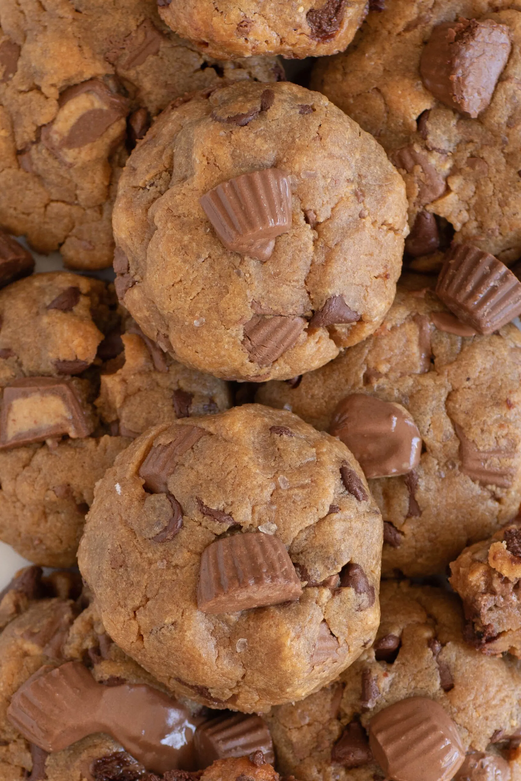 up close view of thick peanut butter cup cookies stacked together on a plate