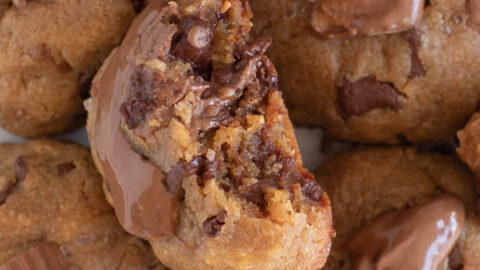 up close view of thick peanut butter cup cookies, one with a bite taken out in the center