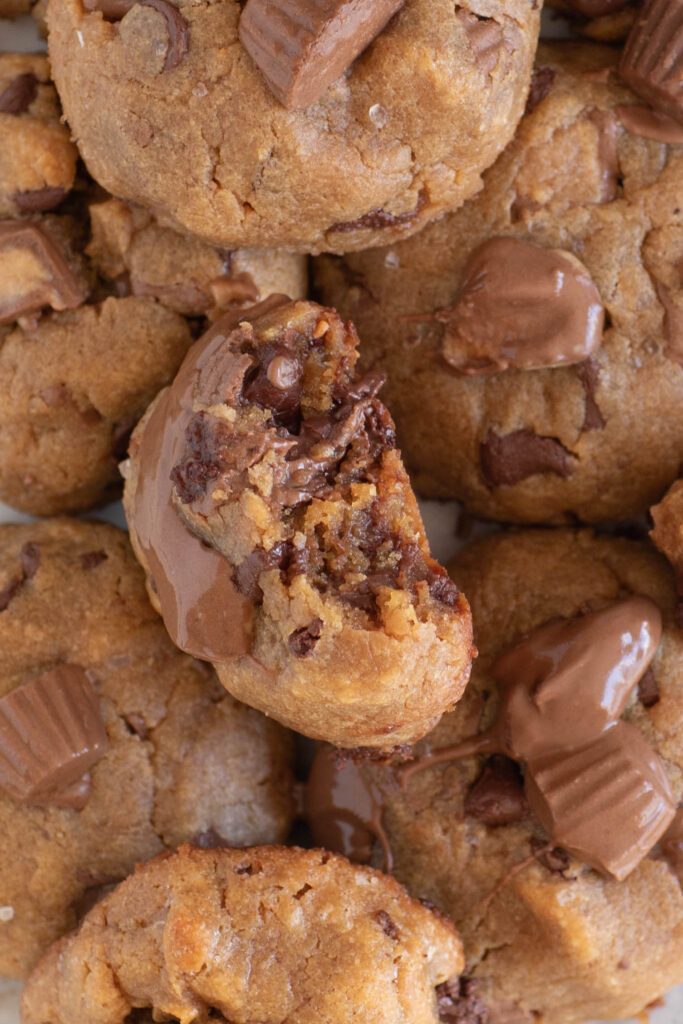 up close view of thick peanut butter cup cookies, one with a bite taken out in the center