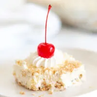up close slice of pineapple vanilla wafer dessert with a fork bite taken out of it. Topped with pretty whipped cream and a cherry.