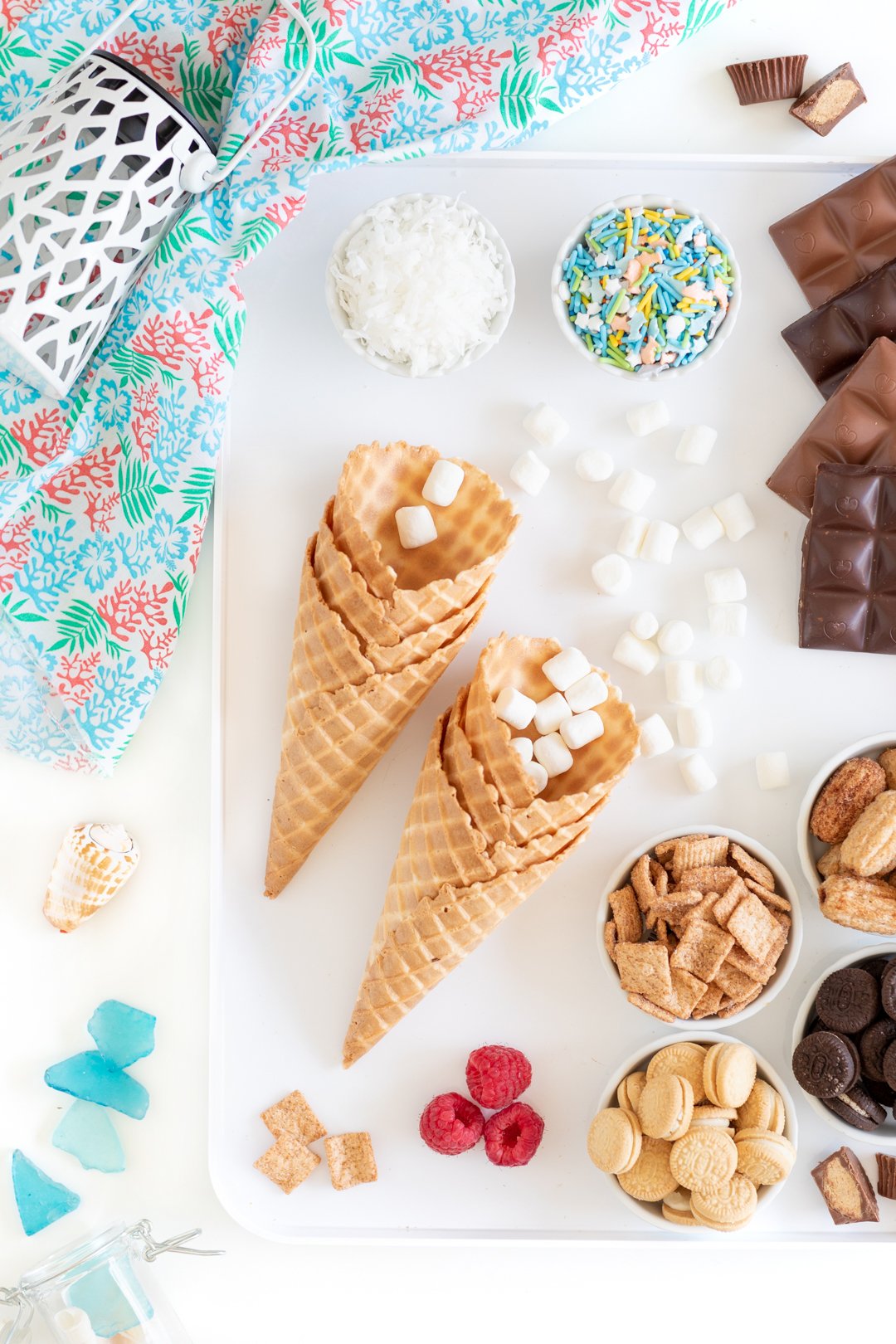 dessert tray to make campfire cones with waffle ice cream cones, mini marshmallows, mini cookies, chocolate bars, sprinkles, graham cereal and more fillings.