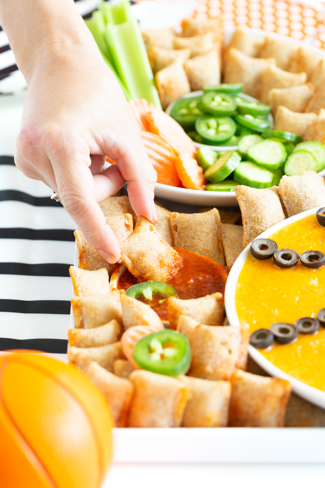 woman dipping a totino's pizza roll into marinara sauce on a basketball charcuterie board