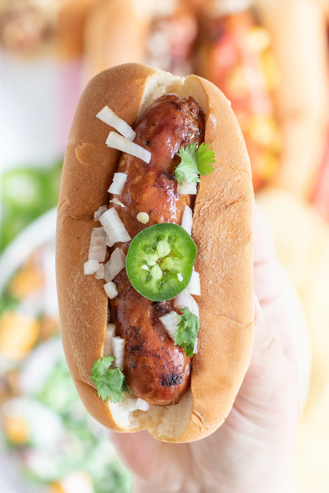 up close view of grilled cajun sausage topped with chopped onions, jalapeño slices and cilantro