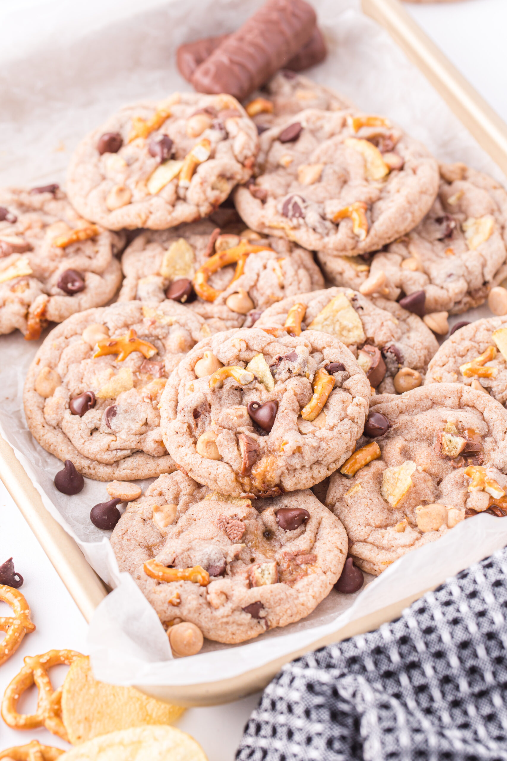 up close baking sheet that is loaded with kitchen sink cookies piled onto each other