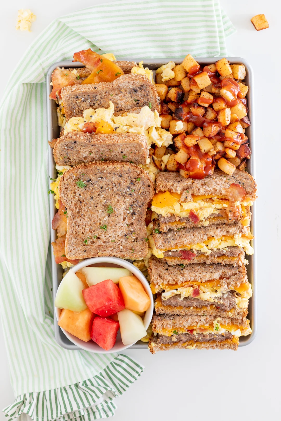 breakfast sandwich charcuterie board with home fries and fruit salad