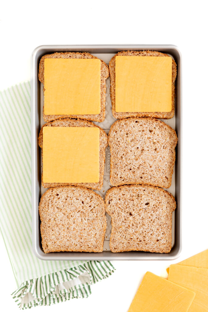 6 slices of bread topped with cheddar cheese on a small baking sheet