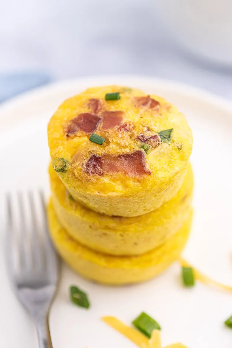 stack of three egg cups made in a muffin tin using chives and bacon