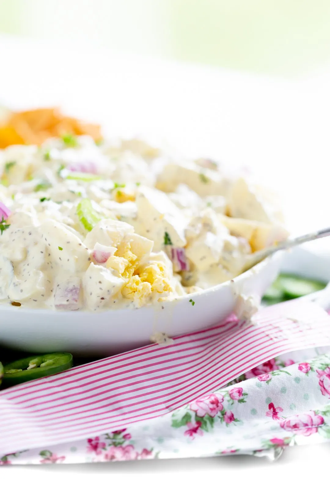 up close view of potato salad being served for summer. chopped celery, chopped red onion, parsley, chopped boiled eggs