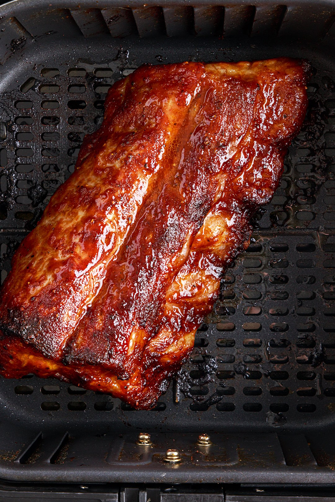 slab of cooked bbq ribs in an air fryer basket