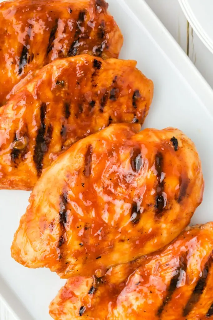 over head photo of grilled barbecue chicken breasts on a white plate