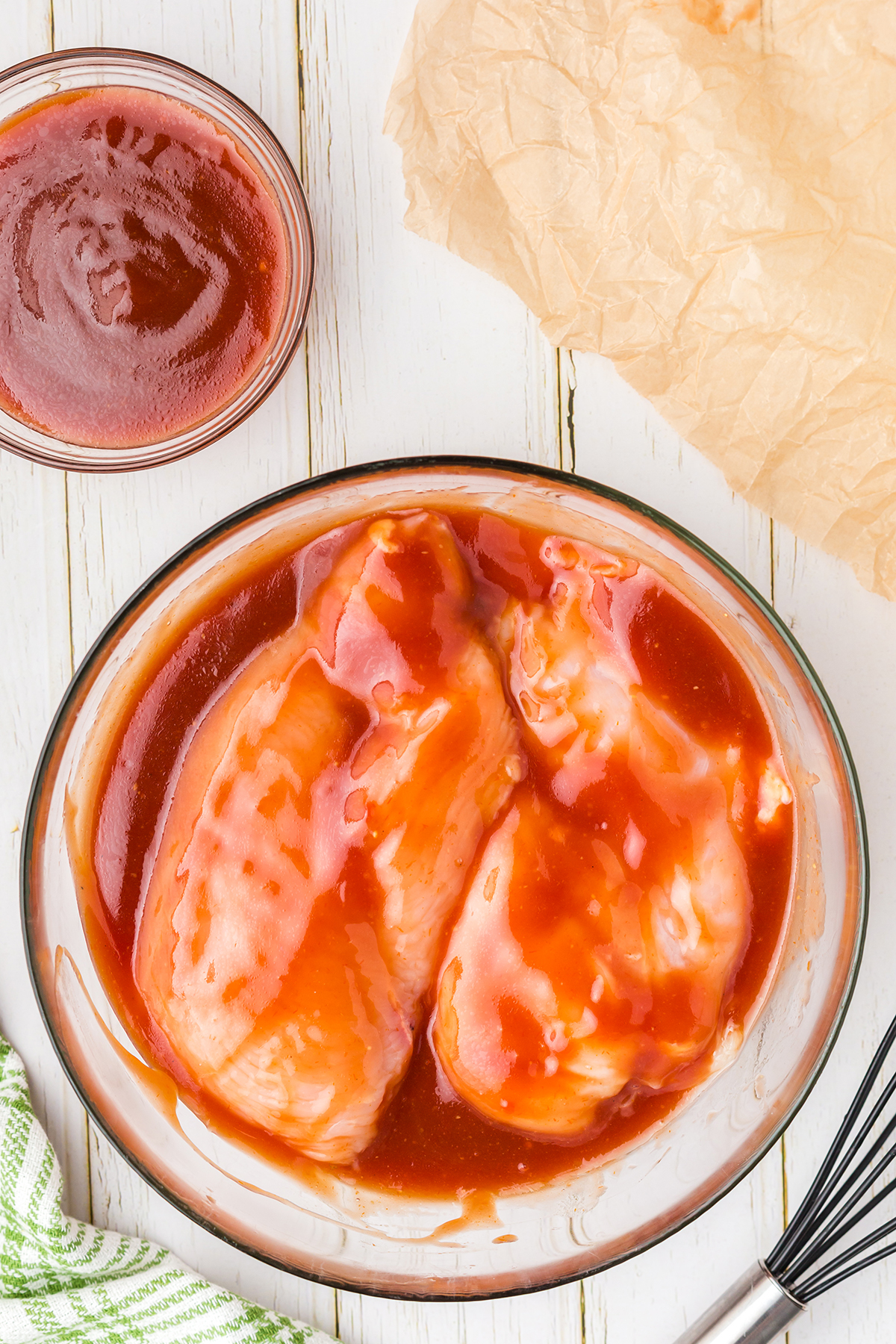 boneless chicken breasts marinating in a bowl of bbq sauce