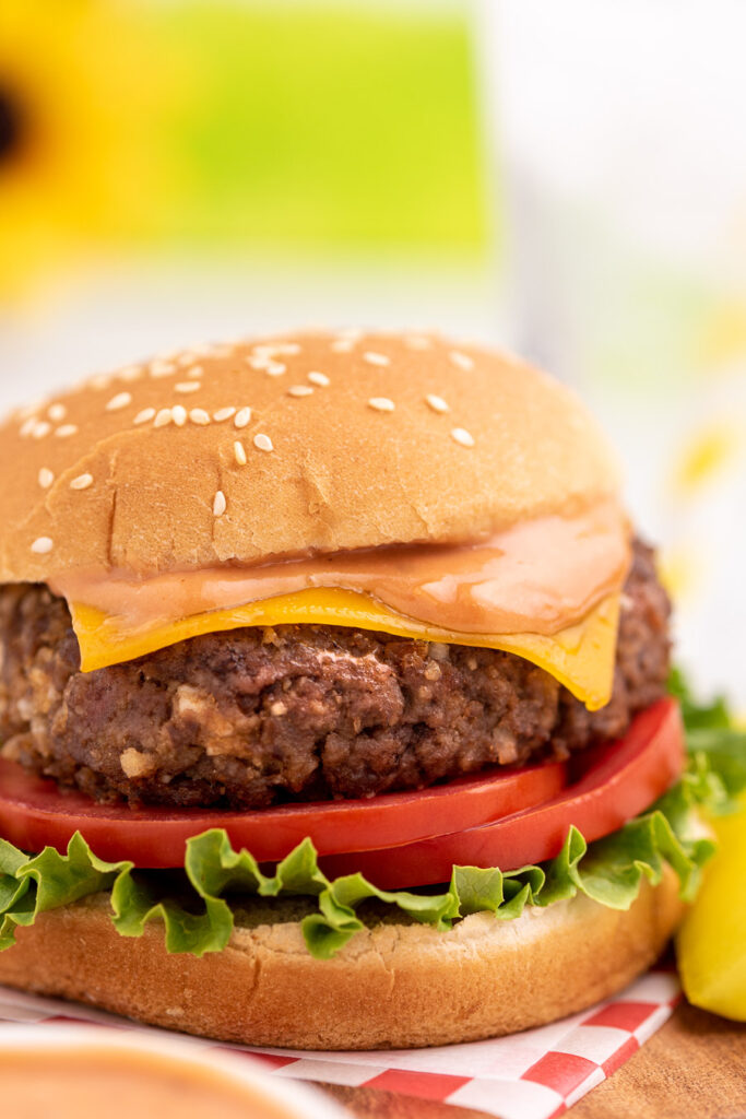 lipton onion mix burger served on lettuce and tomato slices, topped with cheese and special sauce on a bun