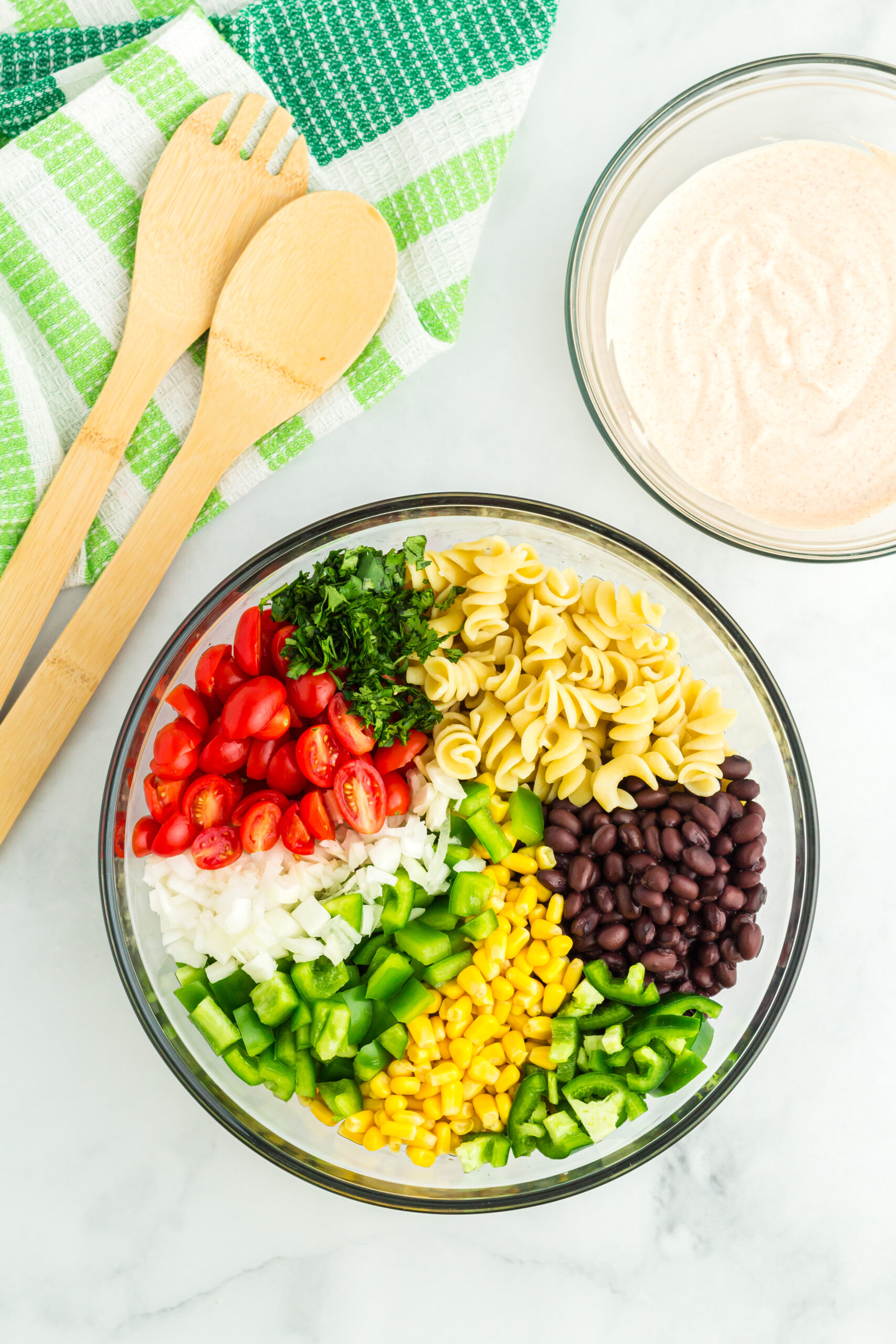 southwest pasta salad ingredients placed in a glass bowl before mixing