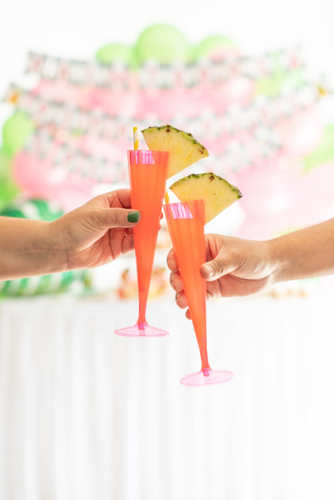 two bright pink novelty cups with pineapple wedges