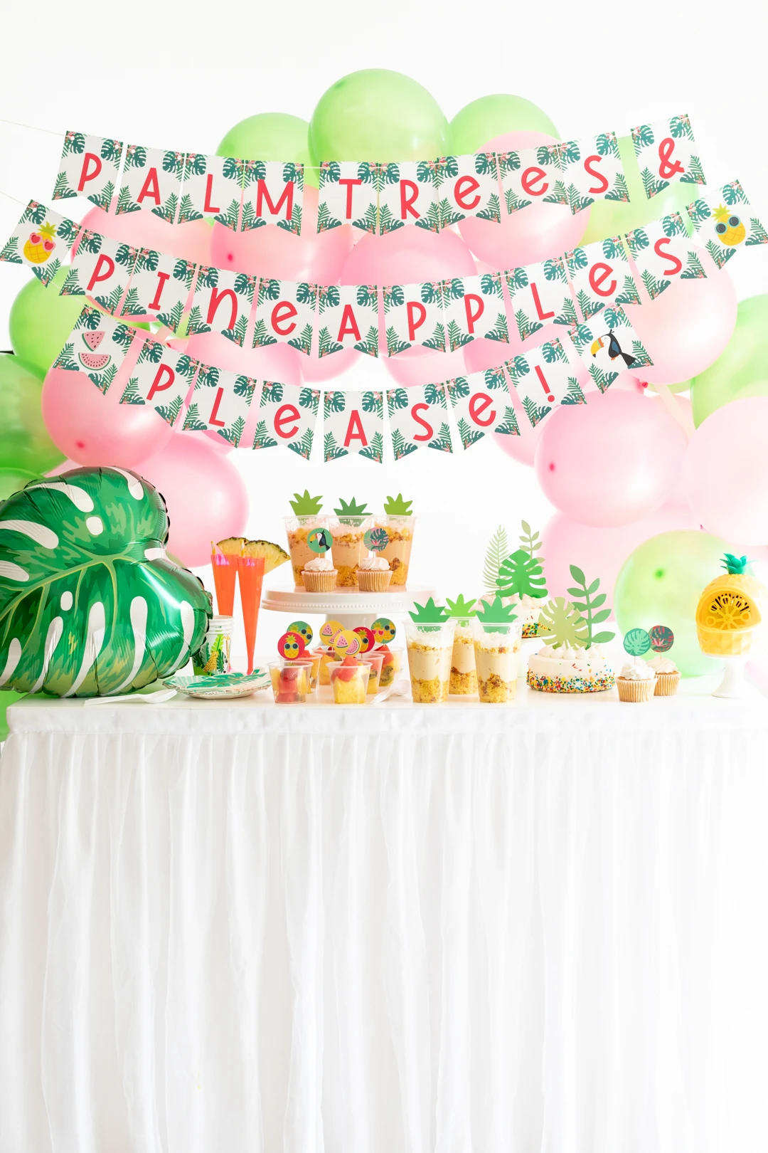 tropical party table with palm trees and pineapples, please banner