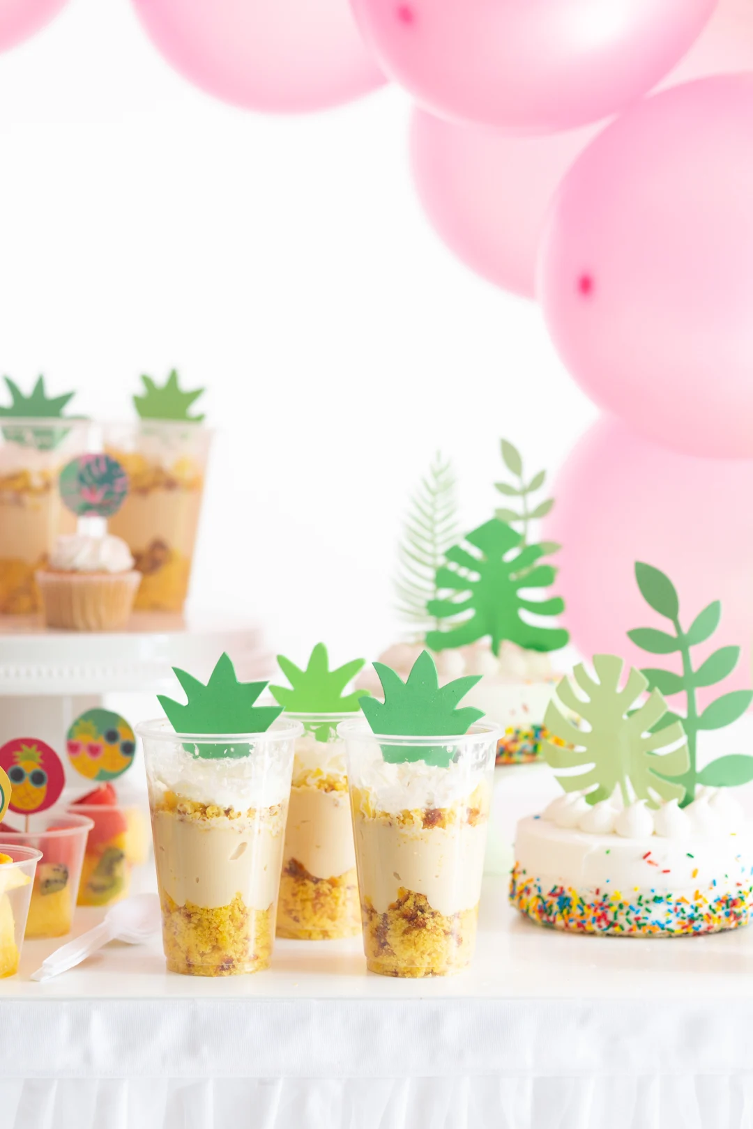 decorated tropical party table with simple themed desserts with palm toppers