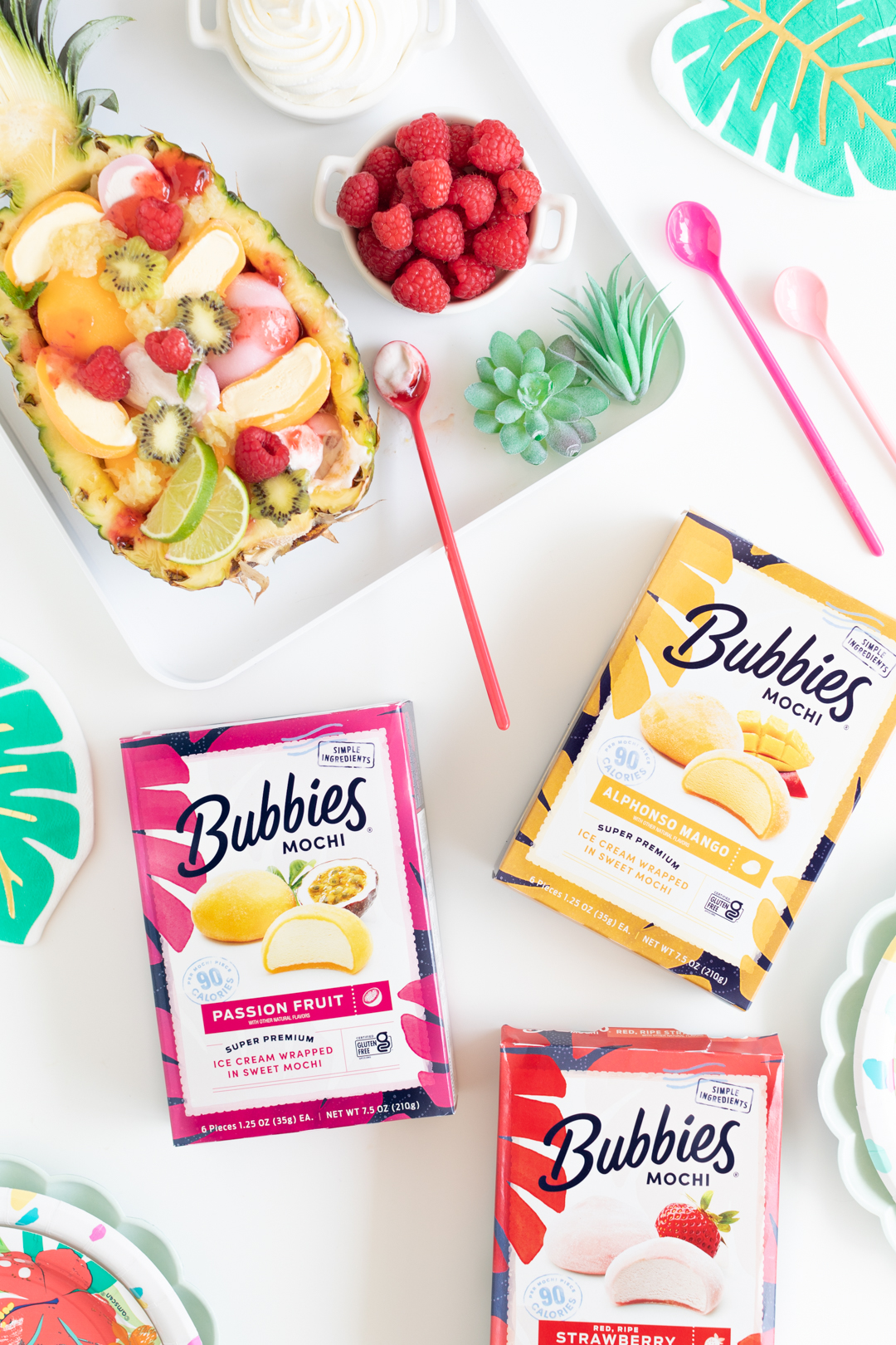 Variety of Bubbies Mochi product boxes with halved pineapple sundae made with mochi served on a tray