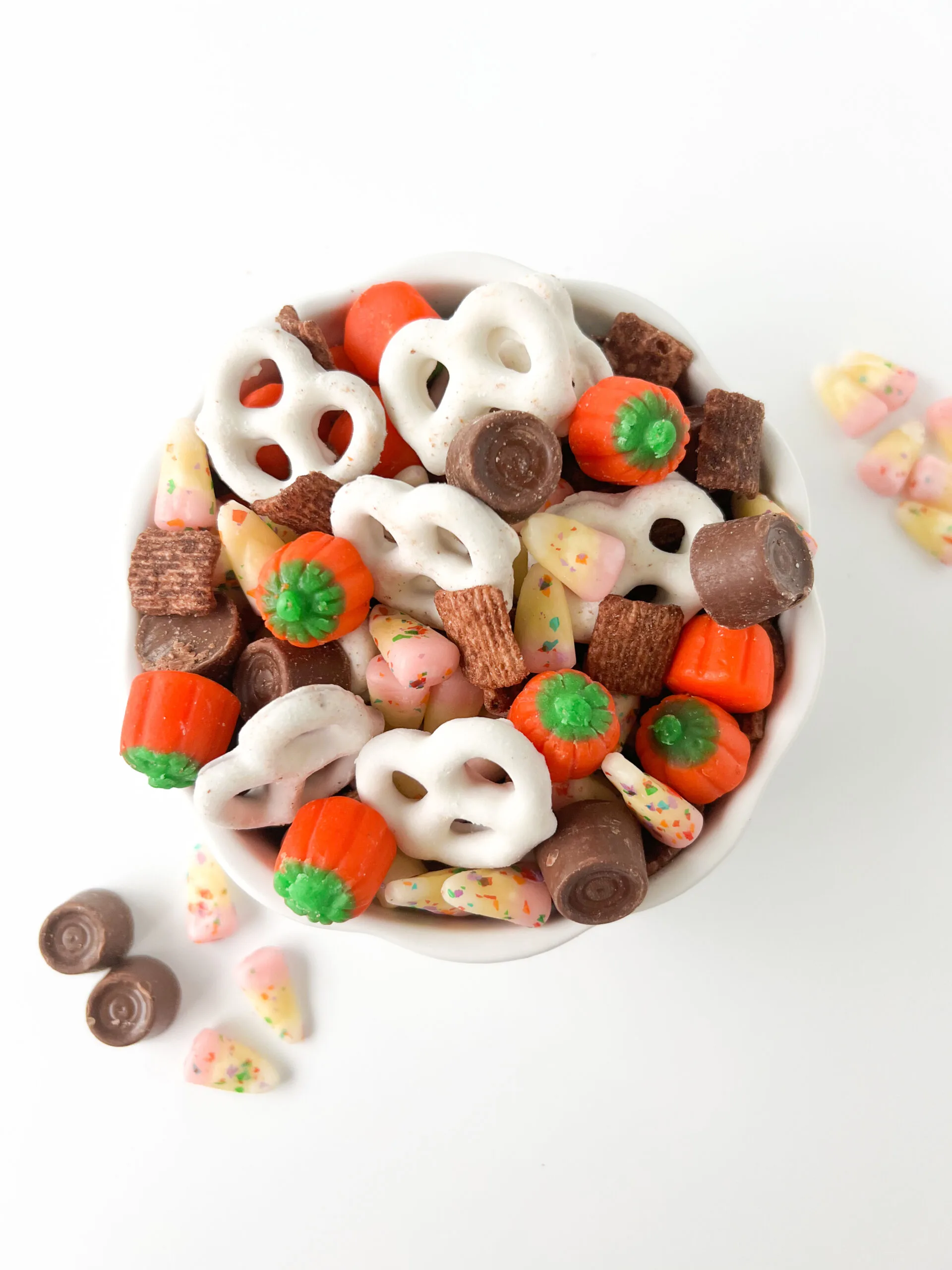 small dish filled with snack mix with yogurt pretzels, chocolate cereal, candy corn pumpkins, funfetti candy corn, rolos 
