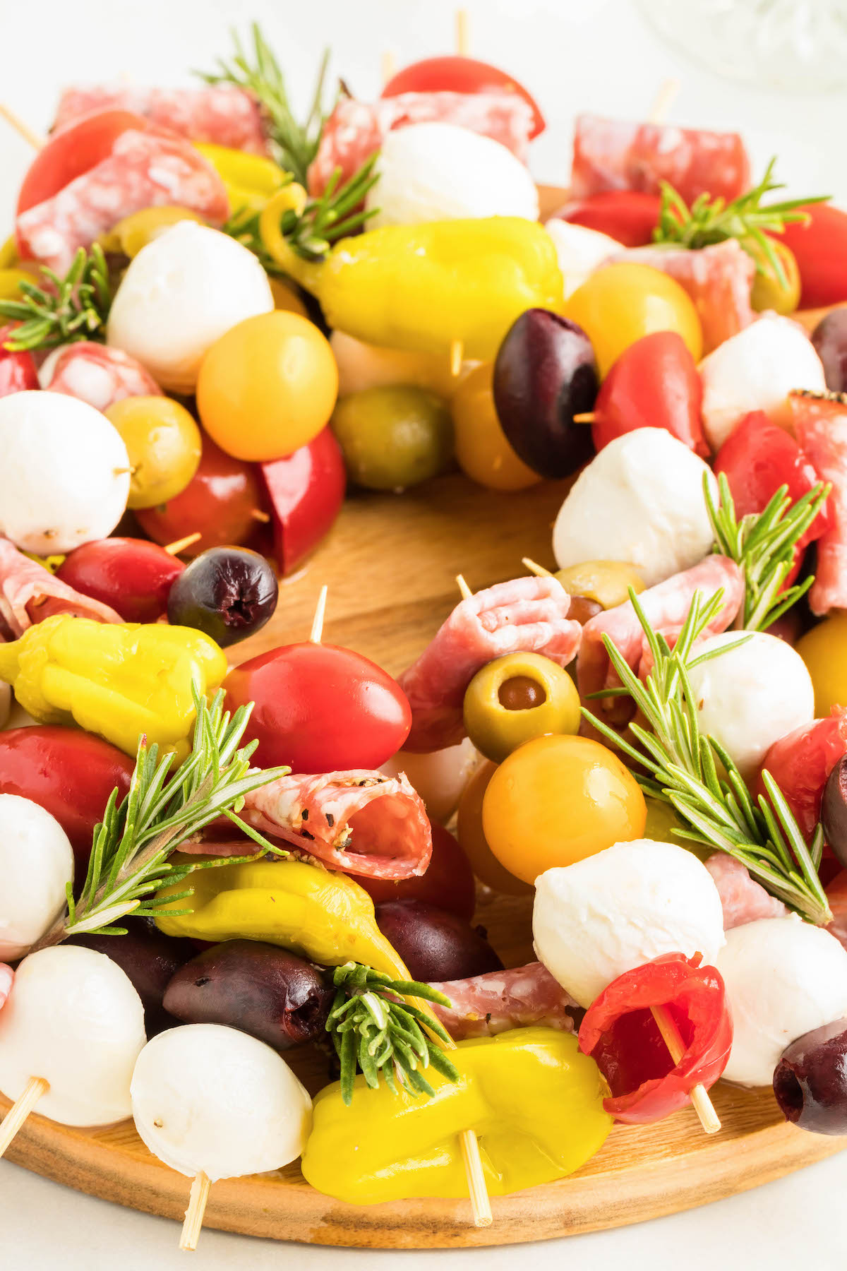 up close angled photo of a antipasto wreath with tomatoes, fresh mozzarella and cherry peppers