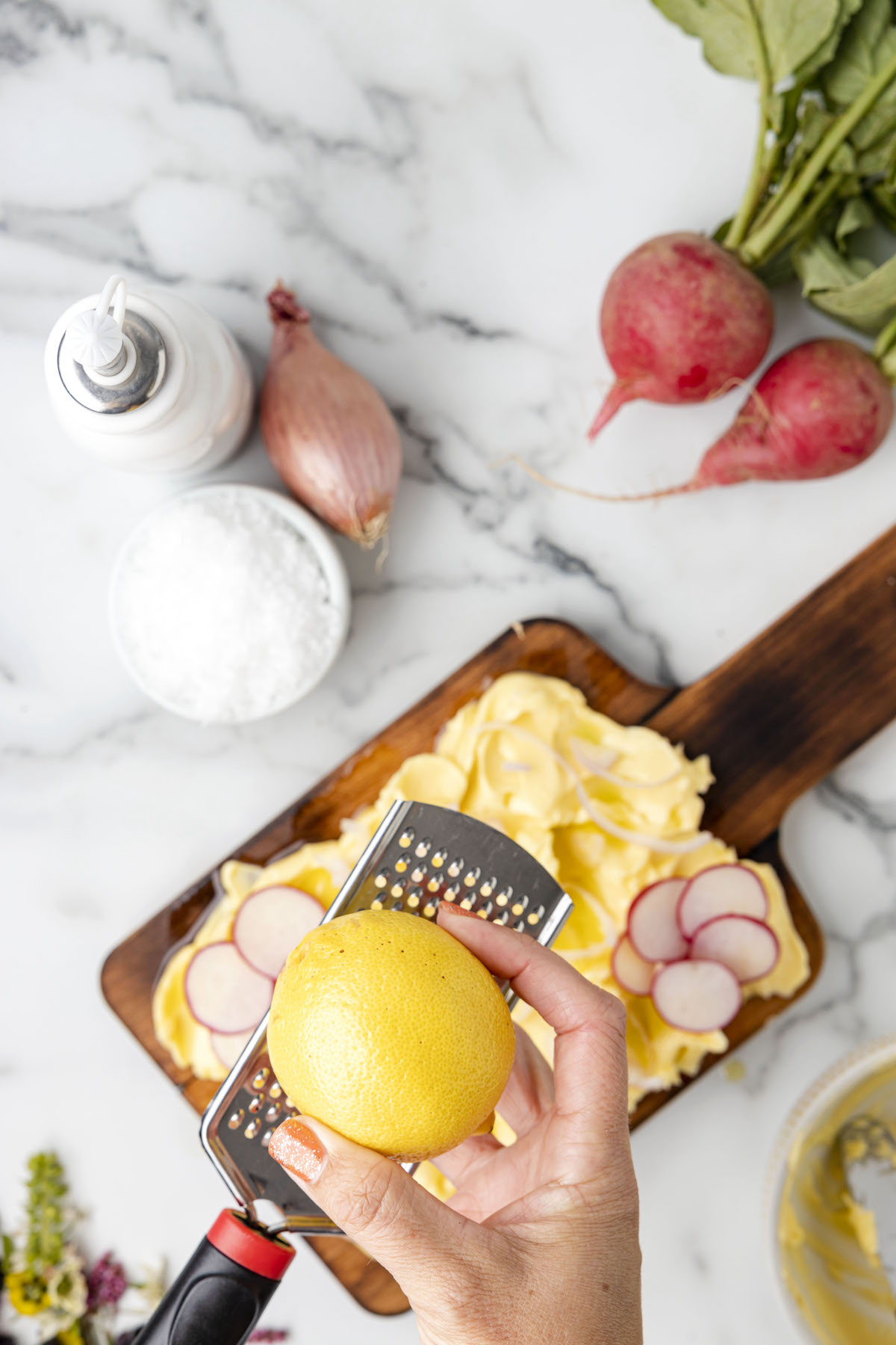 zesting a lemon with a grater over a butter board