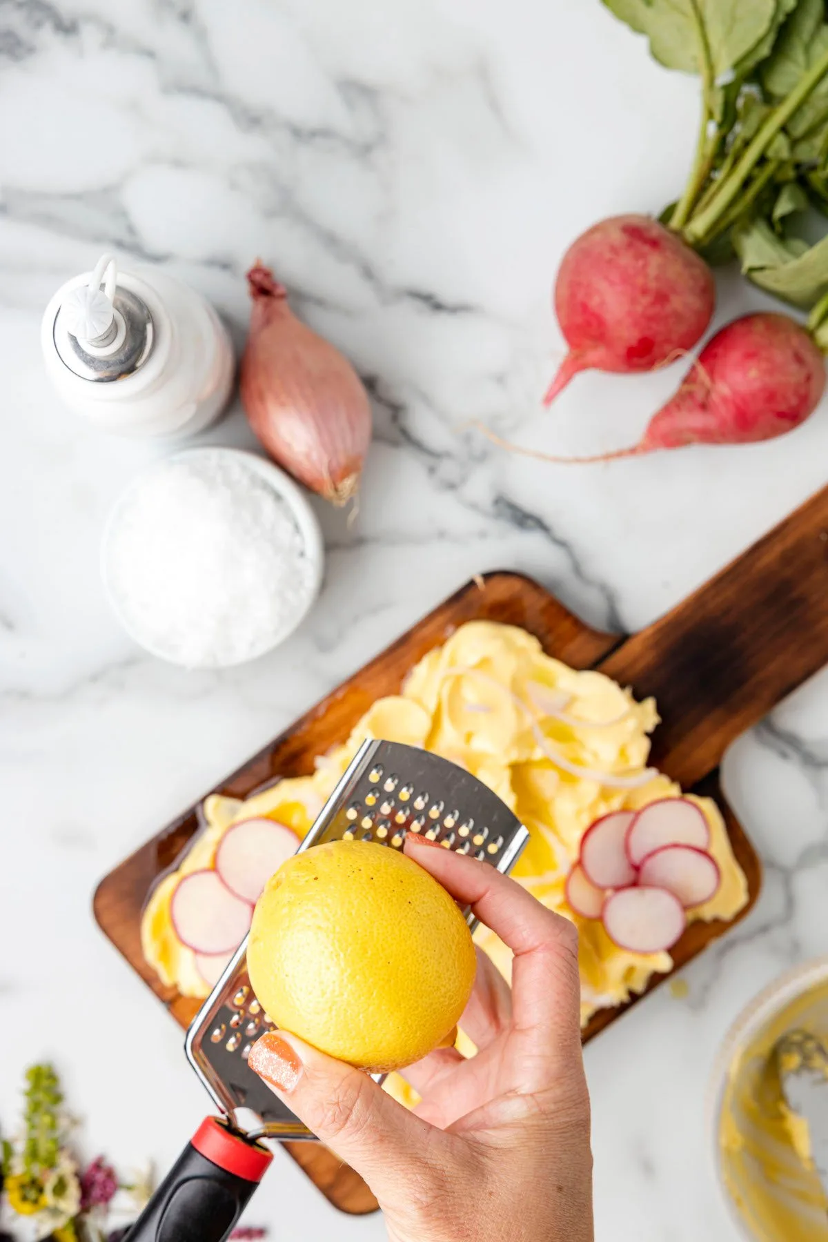 zesting a lemon with a grater over a butter board