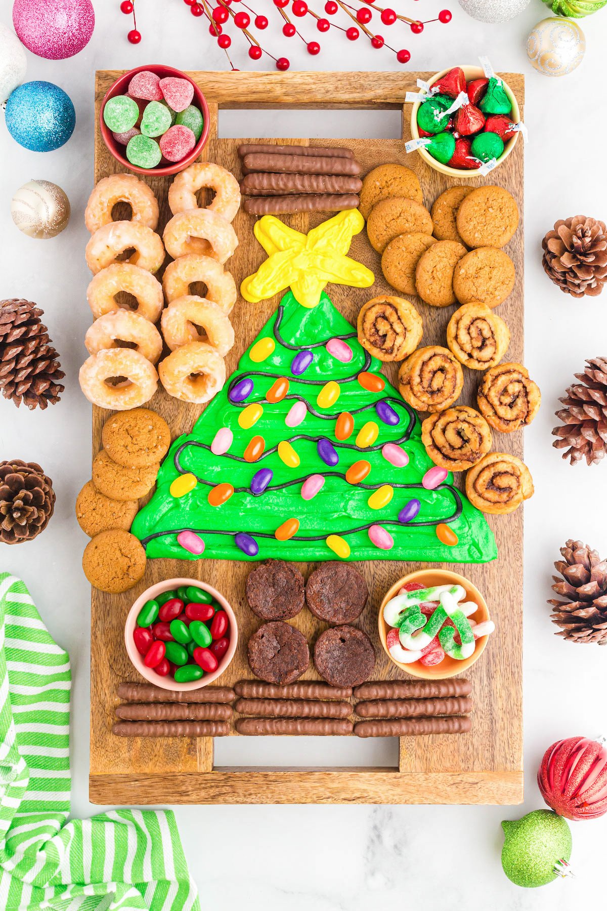 buttercream board with a christmas tree on it and cookies and donuts to dip into it